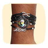 Unicorn charm bracelet with multi-strand black faux leather and silver-tone 'Love' and infinity charms, worn on wrist. Trendy & adjustable fit.