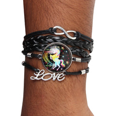 Close-up of trendy unicorn charm bracelet on wrist, showcasing braided faux leather strands, infinity symbol, and vibrant unicorn design.