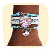 Unicorn Charm Bracelet - Stylish Jewelry with blue and white faux leather strands, unicorn centerpiece, and silver-tone charm, worn on wrist.