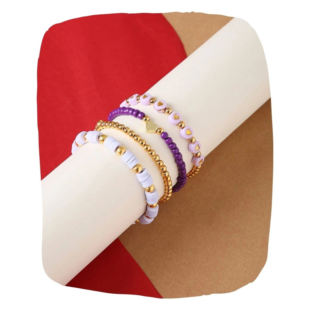 Lavender Haze Stackable Clay Bead Bracelet Set featuring four boho-style bracelets with purple, gold, and heart accents on a display roll.