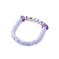 Close-up of 'SMILE' clay bead bracelet from the Cotton Candy Skies Stack, featuring purple, white, and grape-themed accents for a playful look.