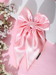 Pink satin hair bow with long tails displayed on a pink background, ideal for stylish and secure hair accessorizing.