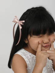 Light pink satin silk ribbon hair bow worn by a girl with straight black hair. Secure and stylish handmade accessory for kids.