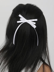 White satin silk ribbon hair bow clipped on long black hair. Elegant handmade hair accessory perfect for formal or casual looks.