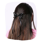 Elegant Handmade Satin Silk Hair Bow in black styled on long brown hair. Adds charm and comfort to women's hairstyles for any occasion.