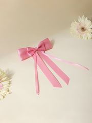 Pink satin silk ribbon hair bow with double bow and long tail design, displayed on a neutral background with floral accents. Perfect for girls' accessories.
