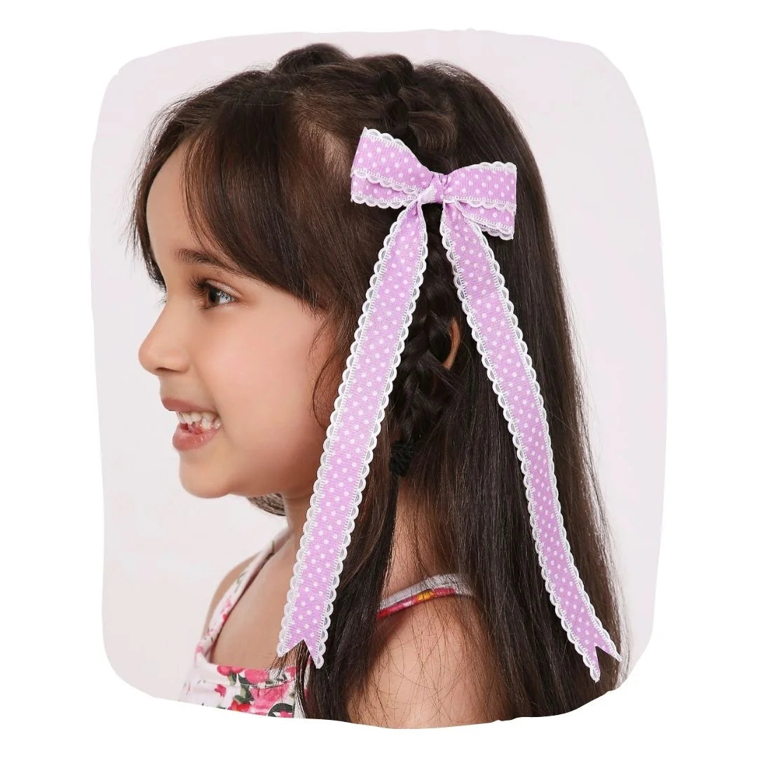 Girl wearing lavender grosgrain polka dot hair bow with scalloped edges. Handmade clip adds charm to kids' hairstyles.