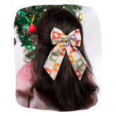 Girl wearing Arendelle Christmas hair bow with festive tree pattern in front of decorated holiday tree. Secure clip fits all ages.