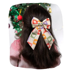 Girl wearing Arendelle Christmas hair bow with festive tree pattern in front of decorated holiday tree. Secure clip fits all ages.