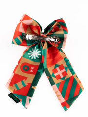 Back view of Christmas hair bow showing secure alligator clip for firm hold. Designed for girls' holiday wear with colorful festive patterns.