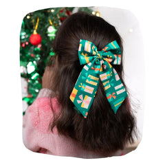 Girl wearing Christmas Gift Hair Bow in green with colorful present prints, styled as a pigtail accessory for festive outfits.