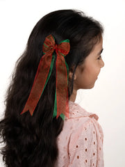 Girl wearing Arendelle's red and green sheer Christmas hair bow, ideal for festive styling with secure alligator clip for ages 3 to 12.