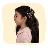 Girl wearing Halloween Collection Hair Bow with black base, orange pumpkins, and white ghosts. Fun, spooky hair accessory for festive outfits.