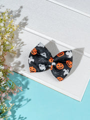 Black Halloween Collection Hair Bow with ghost, pumpkin, and spider web print, styled on white wood background with flowers for seasonal flair.