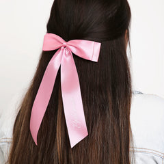 Satin bridesmaid bow in pink clipped on long hair, offering a chic and elegant touch for weddings. Perfect for bridal party styling.
