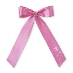 Pink satin bridal hair bow with 'Bride' lettering, perfect for wedding hairstyles and bridal party looks.