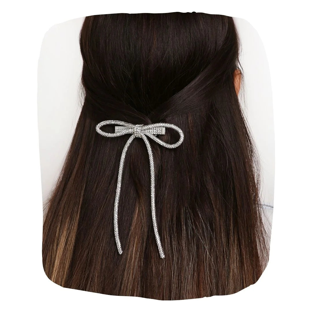 Long Tail Silver Rhinestone Hair Bow clipped onto dark hair, showcasing its elegant sparkle and secure fit for stylish everyday wear.
