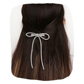 Long Tail Silver Rhinestone Hair Bow clipped onto dark hair, showcasing its elegant sparkle and secure fit for stylish everyday wear.
