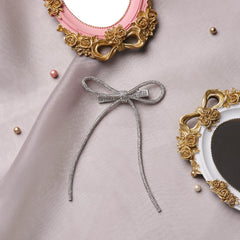 Silver Rhinestone Bow - Handmade Hair Accessory displayed on satin fabric with ornate mirrors, highlighting its luxury and gift-ready appeal.