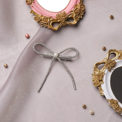 Handmade Rhinestone Hair Bow with pearl center displayed on satin with vintage frames. Elegant hair accessory for gifting or styling.