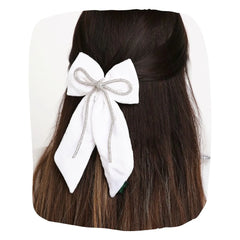 White Rhinestone Hair Bow clipped on long dark hair, showcasing elegant velvet texture and secure hold for stylish everyday wear.