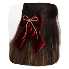 Maroon velvet hair bow with rhinestone cord styled on long dark hair, secured with a sturdy clip for an elegant look.