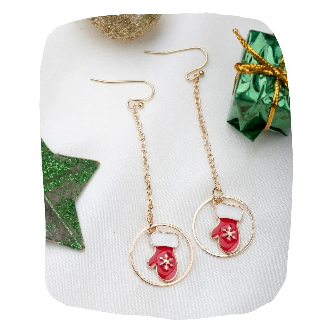 Festive Earrings - Christmas Jewelry featuring red glove and snowflake drop charms on gold chains, styled with gift and star decor.