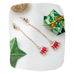Holiday Earrings - Christmas Bell Earrings Women with red double bell charms on gold chains, styled with festive decor for seasonal gifting.