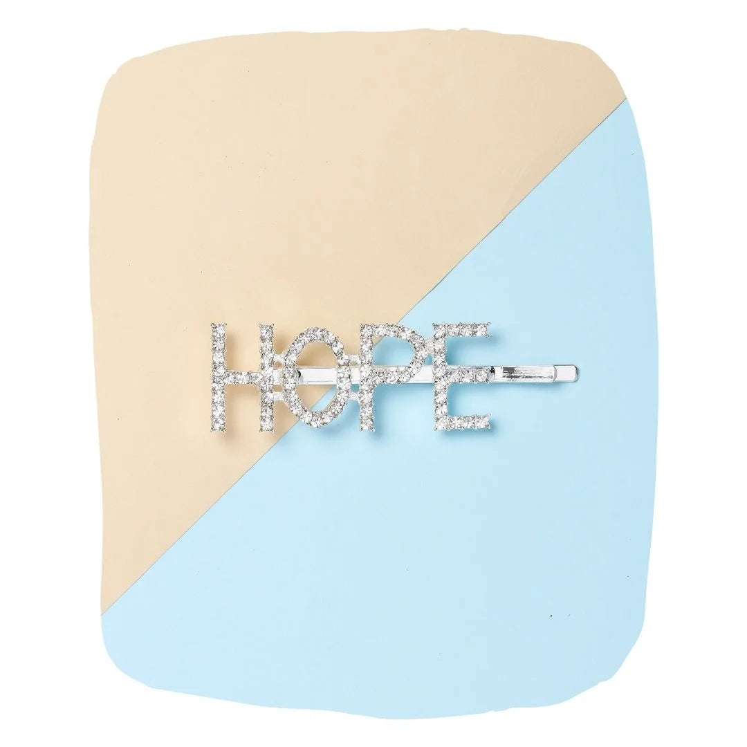Silver glitter HOPE hairpin for girls displayed on a beige and blue background, a trendy clip from Arendelle for stylish hair looks.
