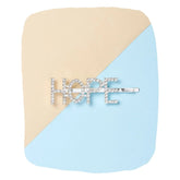 Silver glitter HOPE hairpin for girls displayed on a beige and blue background, a trendy clip from Arendelle for stylish hair looks.