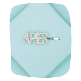 Silver glitter ARIES hairpin with rhinestone lettering on a blue background, perfect for zodiac-themed hair styling.