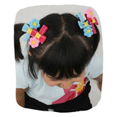 Girl wearing Pompom Flower Hair Clips - Set of 4 in blue and pink with bows and floral accents, ideal for girls aged 3 to 7.