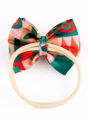 Christmas Baby Headband - Soft & Stretchable | Trendy Designs showing the back view of the red geometric bow on a flexible beige band.