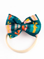 Close-up of Christmas baby headband with green bow and multicolor gift design, perfect holiday accessory for newborns and toddlers.