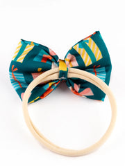 Back view of Christmas baby headband showing soft elastic band and green bow with festive gift print, designed for comfort and style.