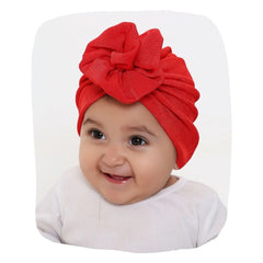 Red Baby Turban Cap on smiling infant, soft stretchable fabric with elegant knot design, ideal for stylish baby wear and comfort.