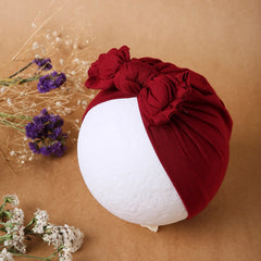 Maroon cotton baby turban with bow knot displayed on a mannequin head. Soft, breathable cap perfect for newborns' everyday wear.