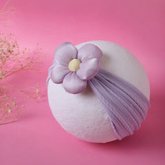 Soft lilac cotton baby headband with padded flower displayed on white sphere. Perfect hair accessory for newborns and toddlers.