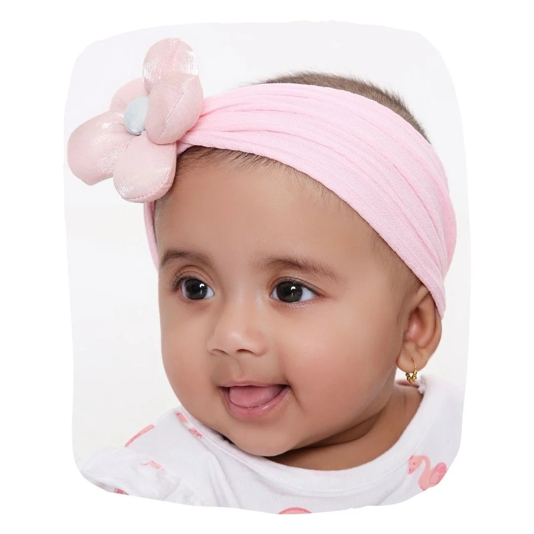 Baby wearing soft pink flower cotton headband, perfect fit and stylish accessory for newborns to toddlers. Stretchable and breathable for comfort.