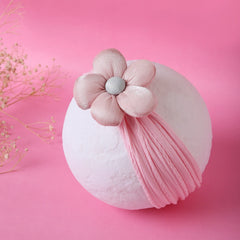 Soft pink baby cotton headband with plush flower detail displayed on a white sphere. Ideal for 0 to 2 years, stylish and gentle on baby skin.