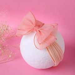 Double layered peach bow cotton baby headband displayed on a white sphere with pink background, perfect for baby girls' outfits.