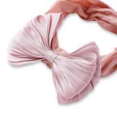 Close-up of rose pink cotton baby headband with pleated double layered bow. Soft, stretchable design perfect for baby girls aged 0-2 years.