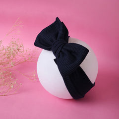 Navy Blue Cotton Baby Headband with large bow displayed on white sphere against pink background, stretchable and comfy for infants and toddlers.