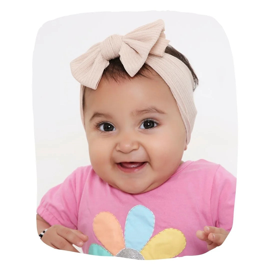 Light brown cotton baby headband with soft bow knot worn by smiling toddler girl. Stretchable and ideal for ages 0 to 2 years.