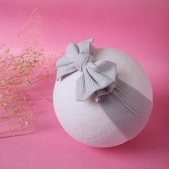 Grey Bow Knot Cotton Baby Headband displayed on white sphere with pink background. Soft, breathable fabric perfect for toddlers and infants.
