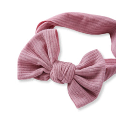 Close-up of light pink cotton baby headband featuring ribbed texture and oversized bow. Ideal for stylish baby outfits and everyday wear.