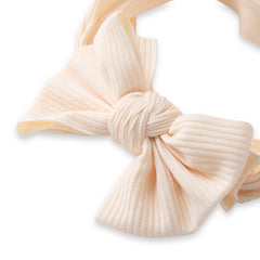 Close-up of beige bow knot on baby cotton headband, showcasing ribbed fabric and detailed knot design for infant girls.