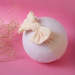 Beige Bow Knot Kids Headband displayed on white sphere with pink background, stretchable cotton accessory for baby girls.