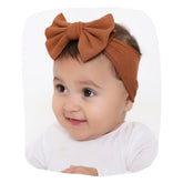 Bronze cotton baby headband with bow knot on infant girl, soft and stretchable for ages 0 to 2 years. Stylish hair accessory for toddlers.