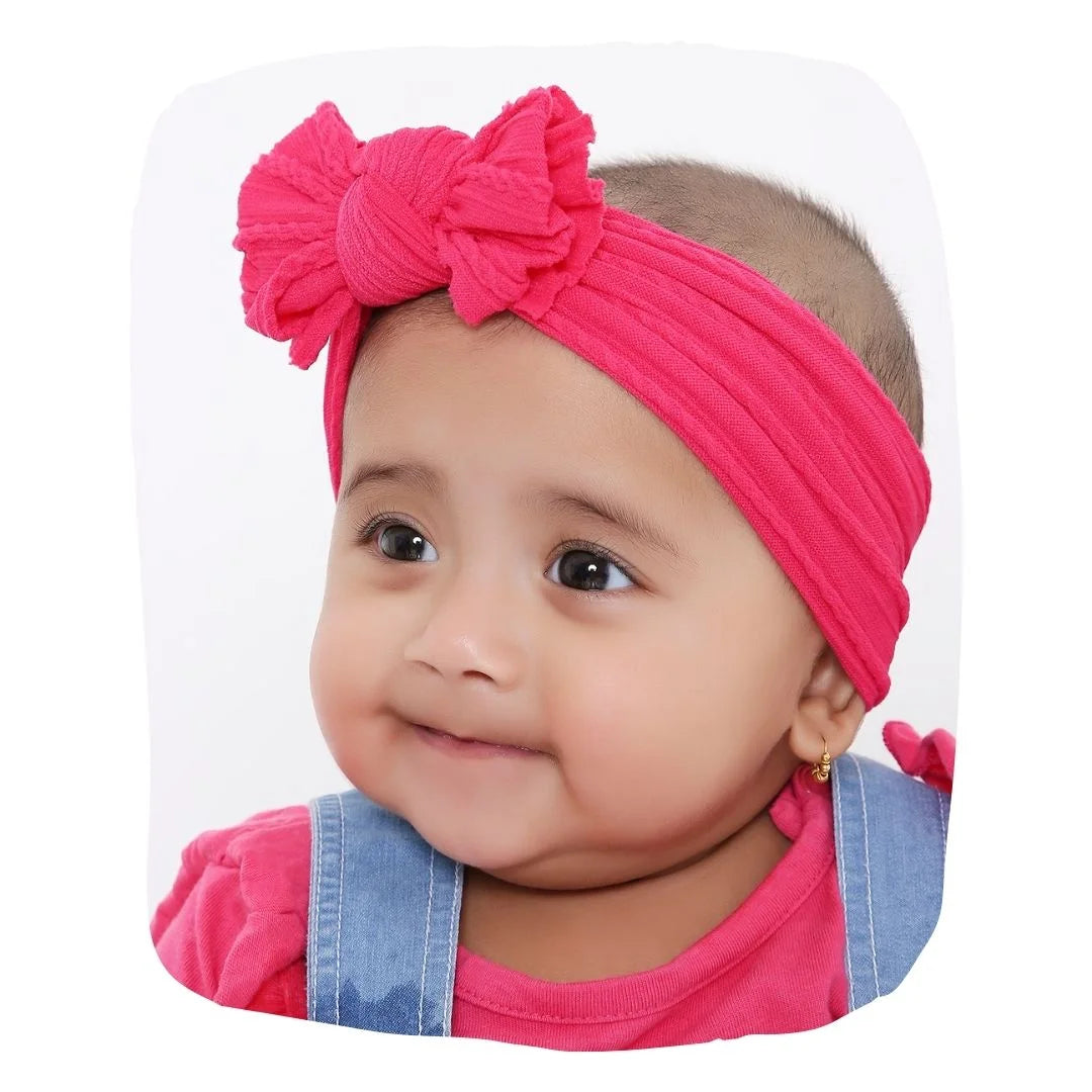 Cotton baby headband in dark pink with large bow, worn by infant girl. Stretchable and soft, ideal for ages 0 to 2 years.